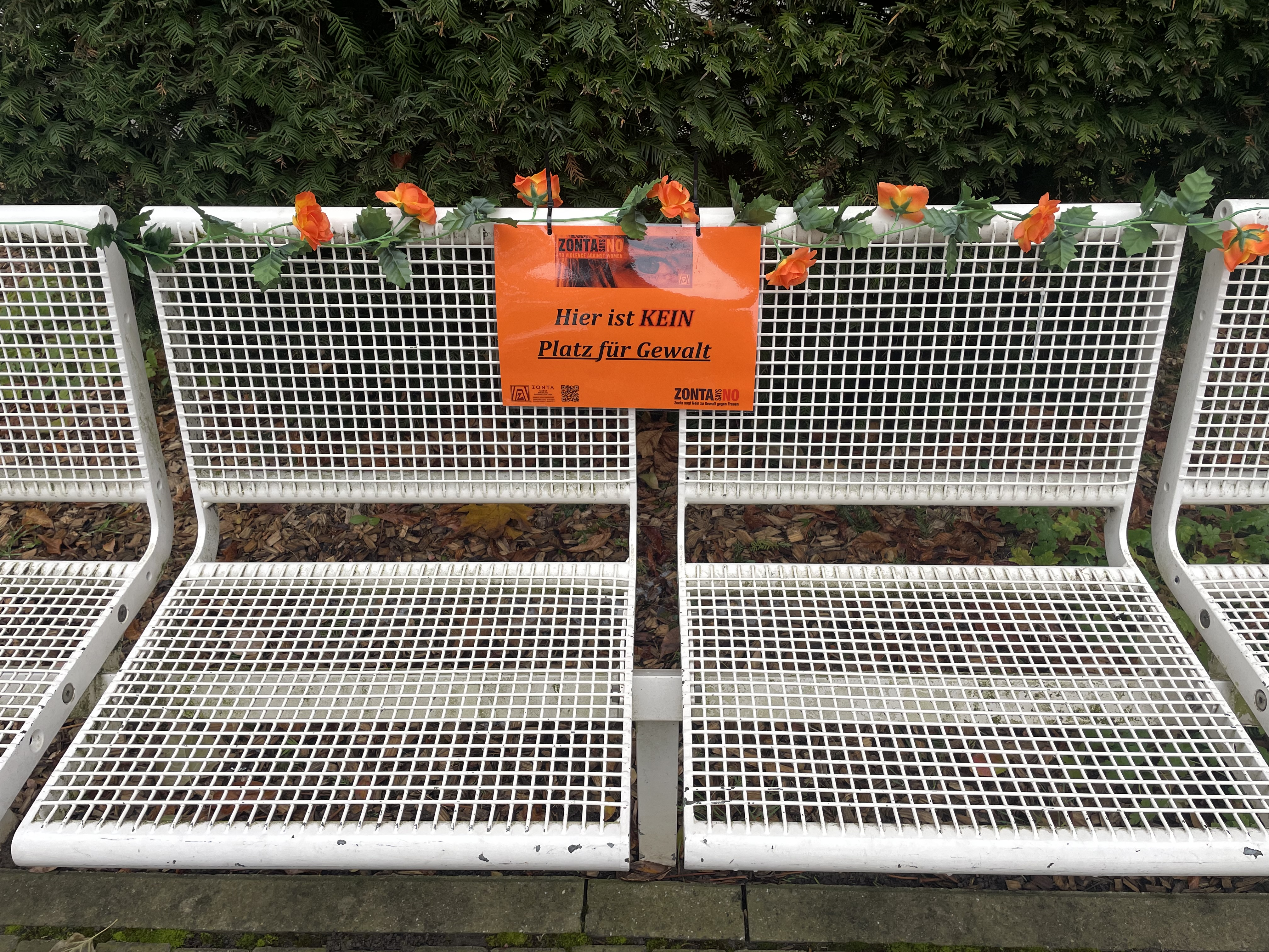 Zu sehen ist eine Parkbank mit einem Schild "Hier ist kein Platz für Gewalt!"