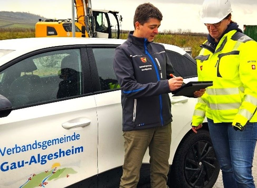 Zu sehen sind zwei Mitarbeiter der Abteilung Bauen und Wohnen bei einem Außentermin.